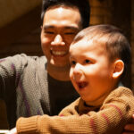 Mies ja lapsi osoittavat käsillä ja nauravat Tiedekeskus Pilkkeessä.