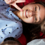 Kaksi nuorta makoilemassa punaisilla säkkituoleilla ja hymyilevät selfietä ottaessa.