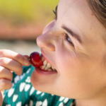 Nainen puraisee maksikkaa iloisena.