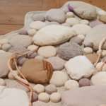 Ruskea ja harmaan sävyisistä kankaista tehty kivikko puulattialla.